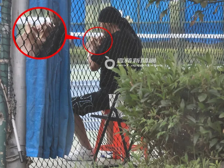 周杰倫坐在球場邊紅色塑膠椅上休息，邊喝插粗吸管的手搖杯飲料解渴補充體力。特勤中心攝