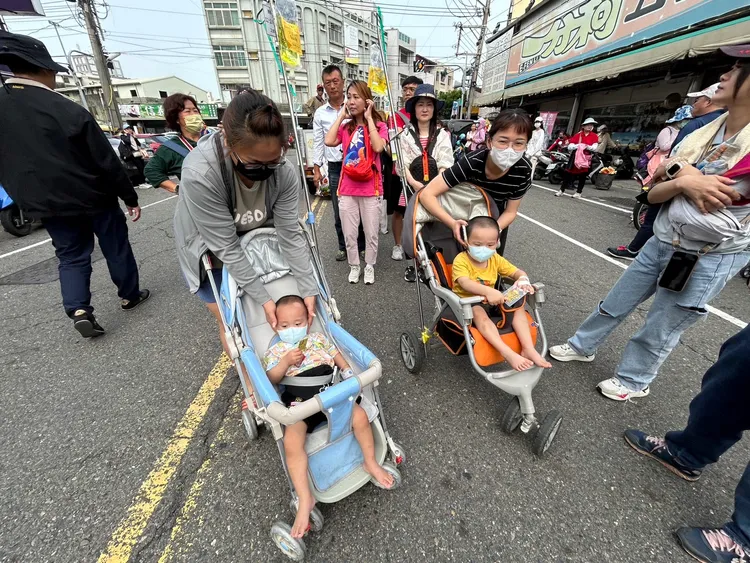 2名罹患肺炎還打著點滴的小朋友，由家人推來向大甲媽祖祈求健康。大甲媽祖教師研習團提供
