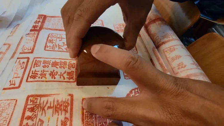 張宏誼將宮廟印章小心翼翼蓋在宣紙上。民眾提供