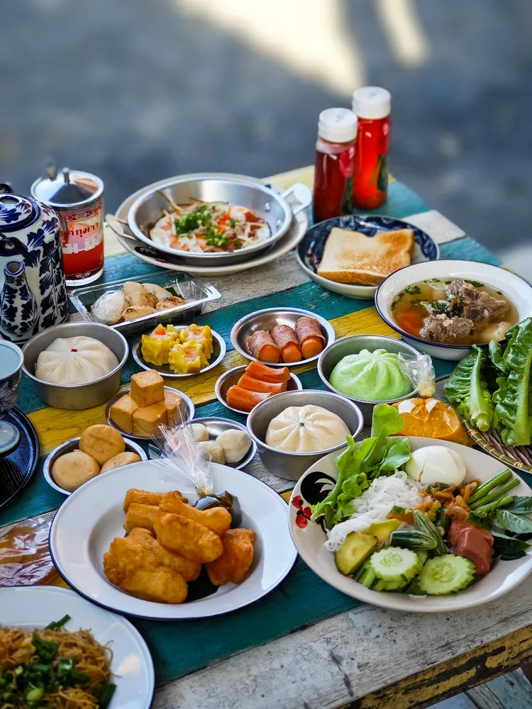 鹹粥、米粉、肉包、點心、泰式油條和菜蔬，各色美味小吃擺滿桌。田欣雲攝