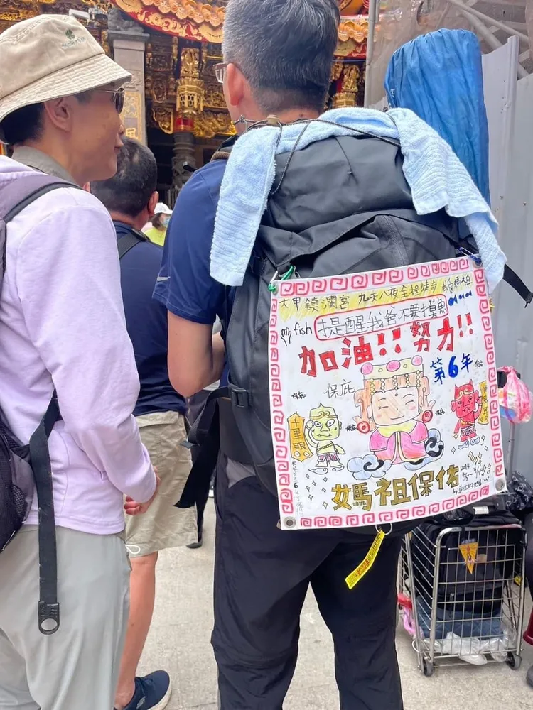 民眾背著女兒的圖畫來遶境。大甲媽祖教師研習團提供