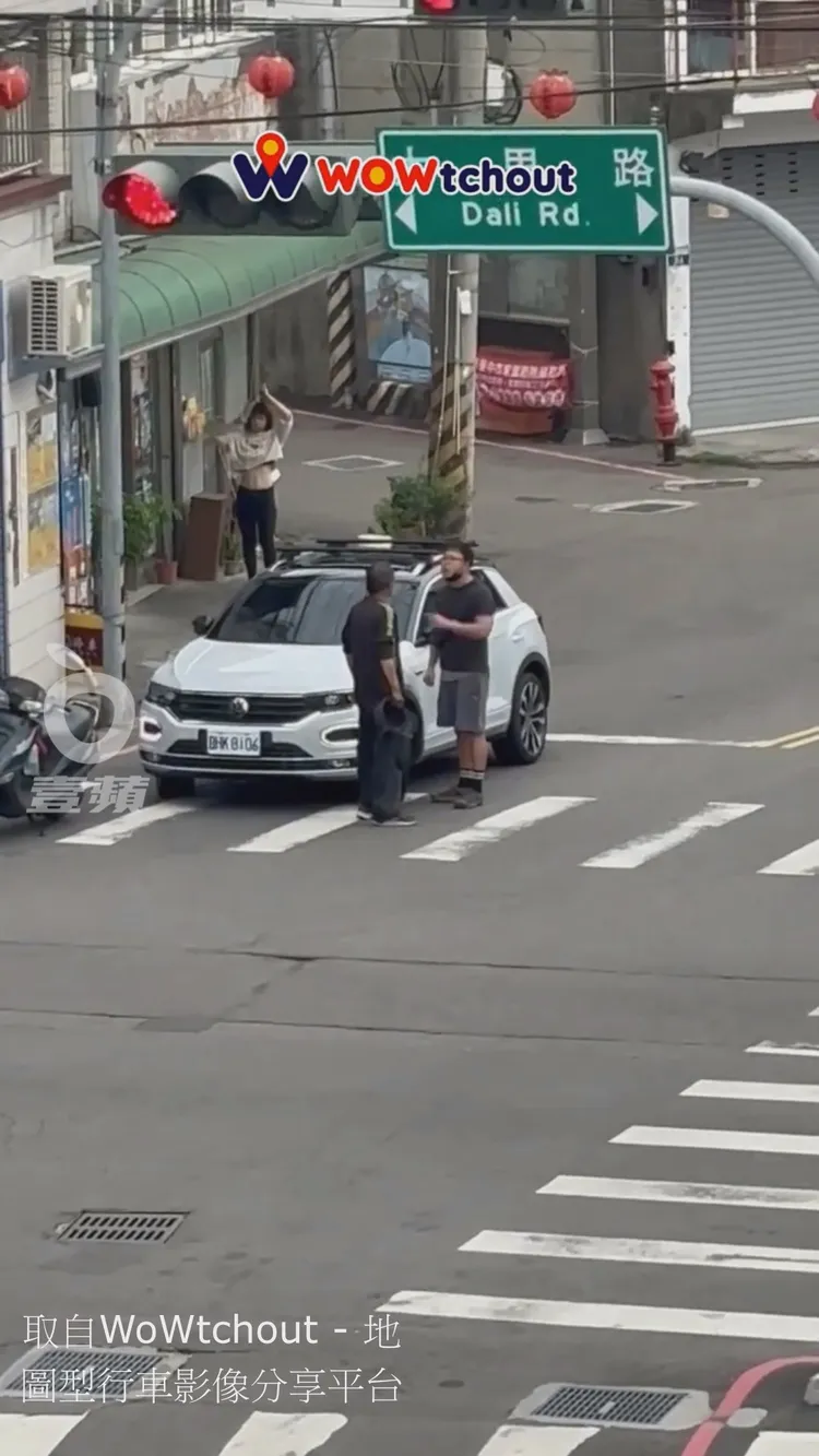 妹子站到騎樓下旁觀行車糾紛，高舉雙手梳髮的舉動，讓她露出結實腹肌纖腰。翻攝自YT頻道「WoWtchout - 地圖型行車影像分享平台」