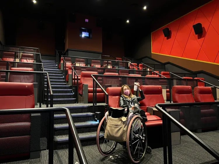 像這種傾斜座椅影廳就必須請工作人員協助，她再自己爬到椅子上。