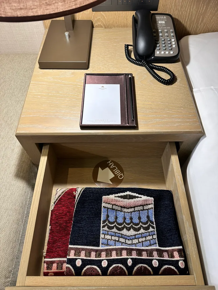 金湖飯店貼心地在房間床頭櫃放置禮拜毯，並貼上指引禮拜方向的貼紙。業者提供