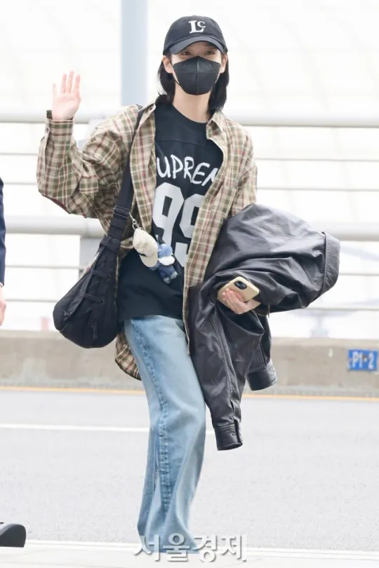 IU看起來心情不錯，揮手打招呼，包包上的娃娃搶眼。翻攝首爾經濟