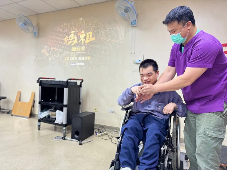 治療師點上線香，讓院生小軒(左)向媽祖祈求家人平安健康。社會局提供