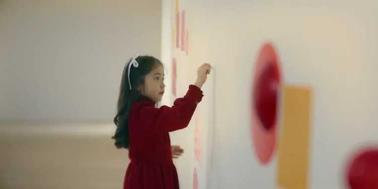 女孩拿起蠟筆在美術館牆上畫畫。富邦提供。