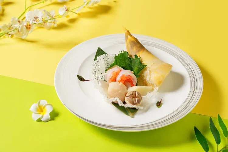 竹筍焗海鮮總匯，陳啟昌主廚以夏季綠竹筍為主菜發想，搭配干貝、蝦仁、花枝焗烤的創新做法，以竹筍的鮮甜搭配焗烤的奶香。業者提供