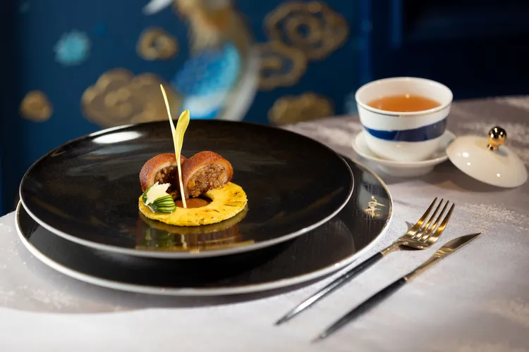 「八寶岩米釀一口乳豬 」以尼泊爾岩米入饌，混合了糯米、肉碎、冬菇、鹹蛋黃、蝦米、芡實和新鮮薏仁一同釀在乳豬內，底部放上一片焦糖化的鳳梨並刷上乳豬醬，搭配以柚子醋浸漬的小黃瓜，清爽酸甜恰好中和乳豬飯的豐厚口感增添層次。業者提供