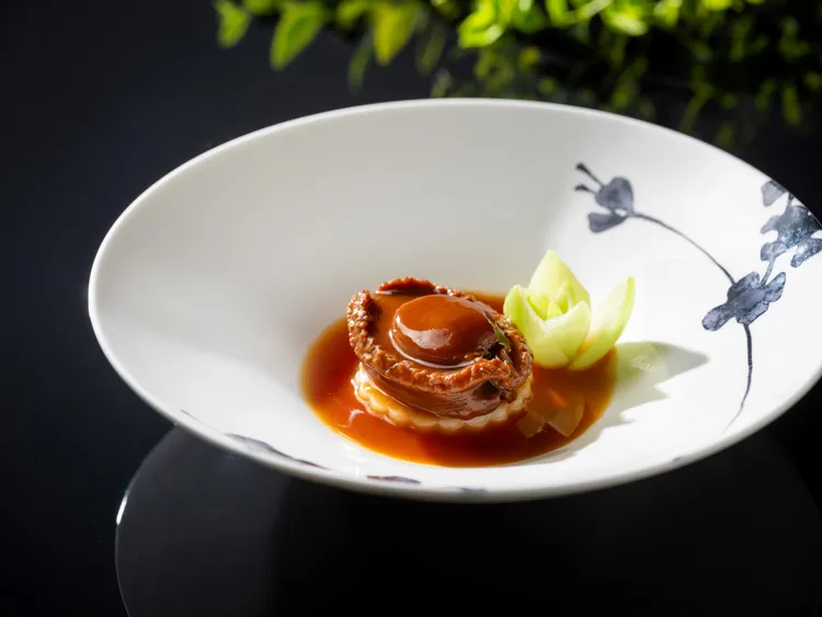 「雅閣」經典「極品日本溏心吉品鮑」鄭主廚選用日本 25頭鮑，將炸出香氣的雞肉、瑤柱、豬肉與雞湯蒸8小時後，再放入清雞湯燜煮2小時，撈出鮑魚後將湯汁勾芡製成醬汁，鮑魚入口鮮甜彈牙，更有幾分溏心口感。業者提供