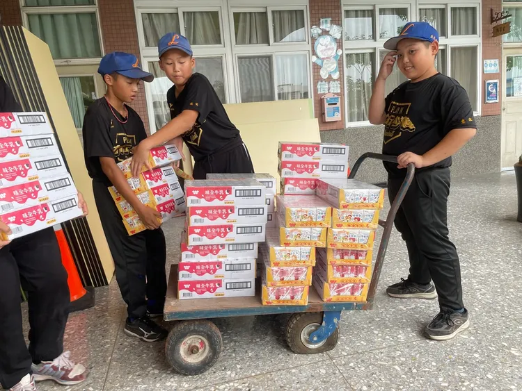 台中市力行國小的小球員開心開心搬運味全保久乳。頂新和德文教基金會提供