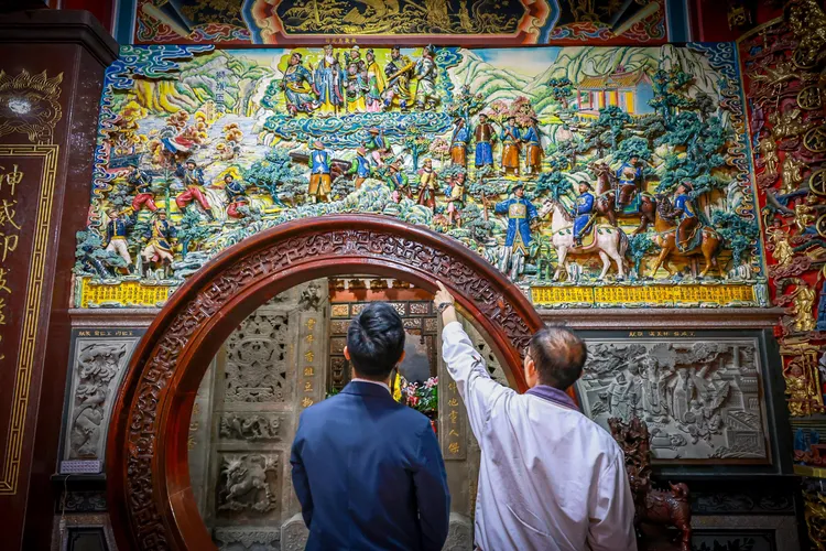 主持人余治明回到獅球嶺平安宮，訪問陳姓廟公顯靈一事。市府提供