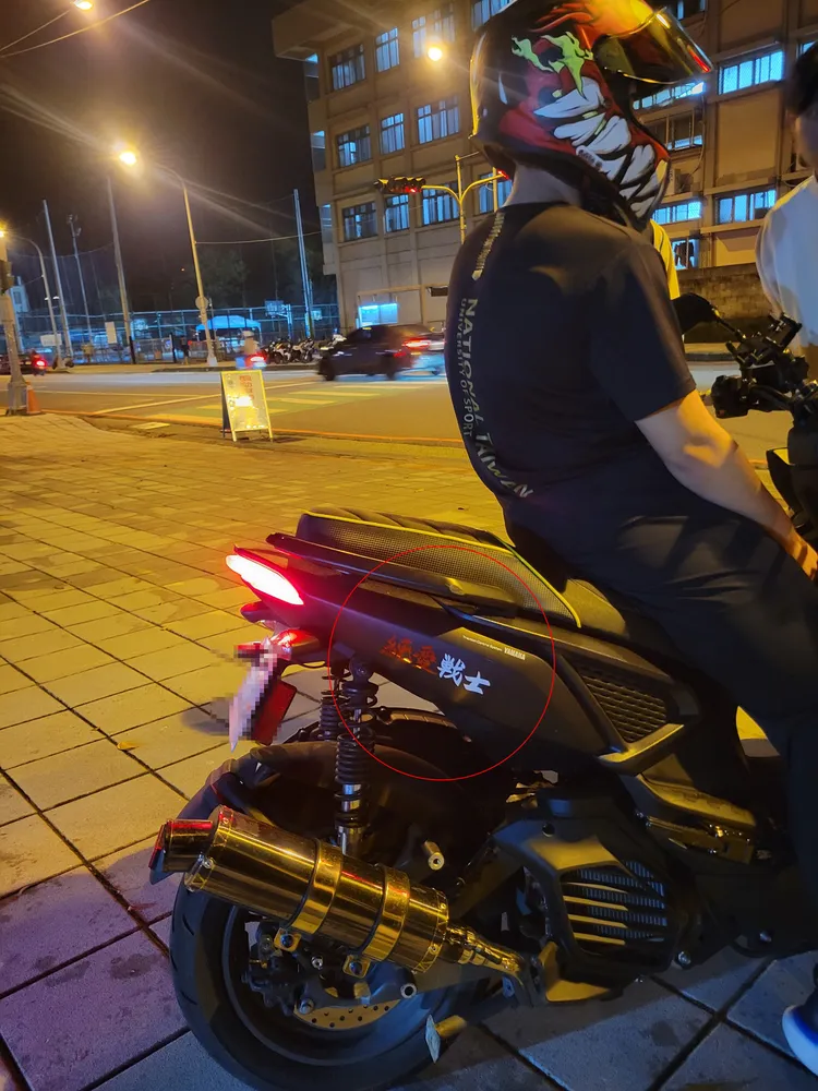 貼有「純愛戰士」的機車，因改裝排氣管及頭燈被攔查。民眾提供