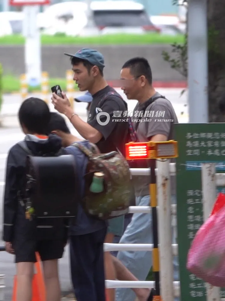 阮經天（左）拿著手機對講，一邊過馬路。特勤中心攝