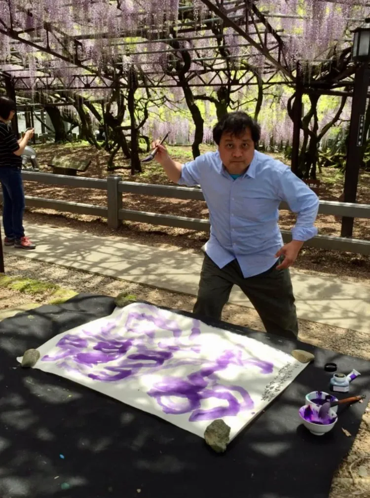 陳世憲在日本九州八女市紫藤花下寫「紫戀」。陳世憲提供