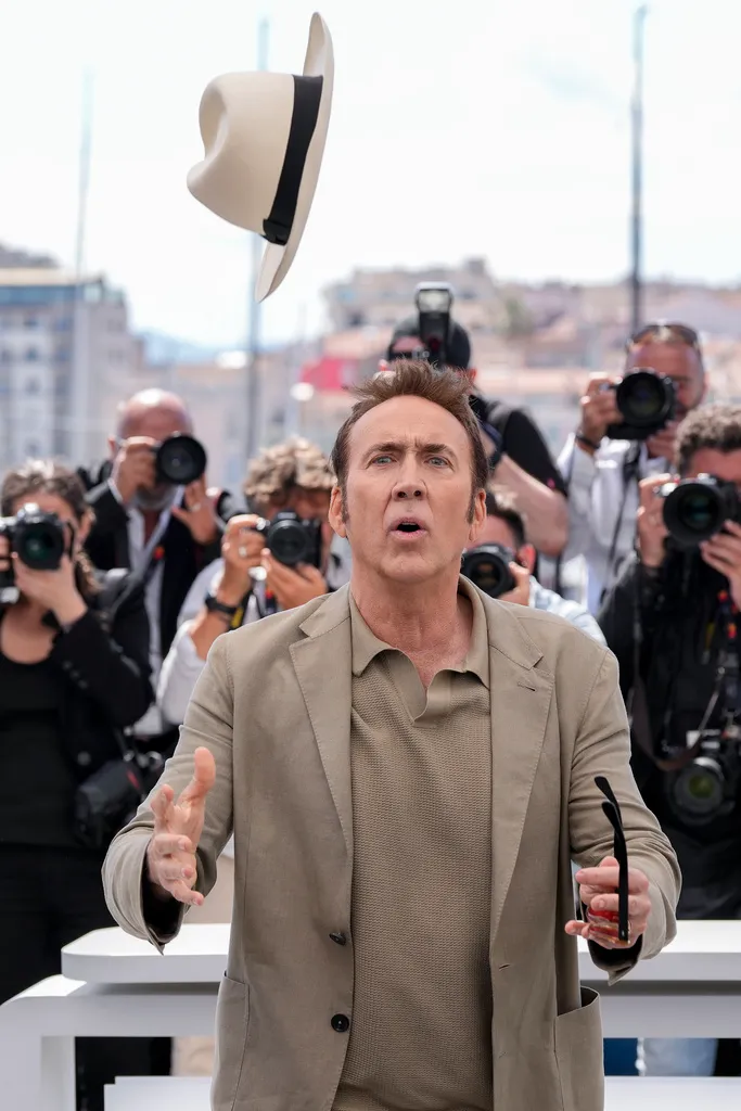 尼可拉斯凱吉在紅毯上大玩丟帽子，每張照片表情都很有戲。美聯社