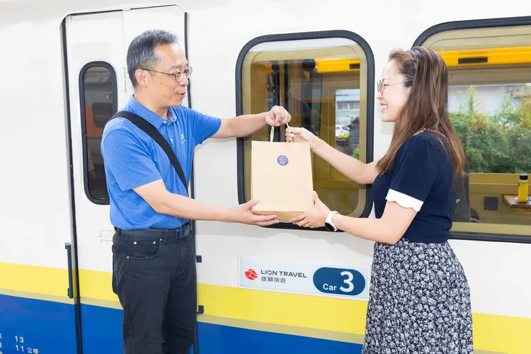 阿里山林鐵處副處長周恆凱贈送旅客首航紀念禮，包括嘉義特產老楊方塊酥餅乾禮盒等。業者提供