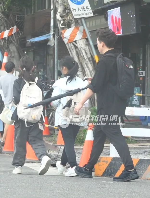 道路修繕，倪安東暖心用雨傘示意女兒和同學靠邊走。特勤中心攝