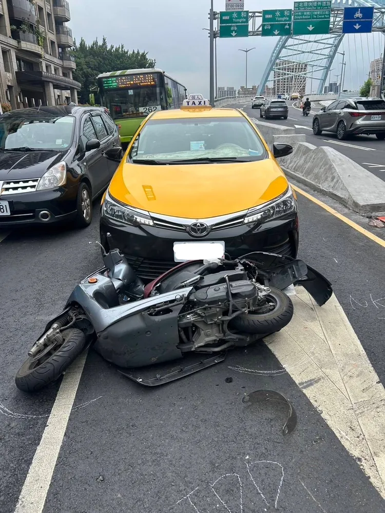 機車卡計程車底。警方提供