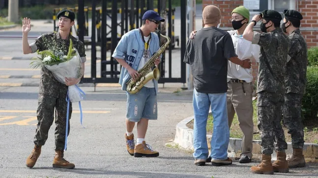 JIN（左起）昨天走出軍營，RM帶著薩克斯風演奏《Dynamite》祝賀。翻攝韓聯社