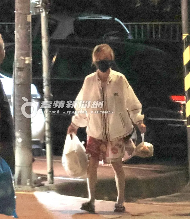 狄鶯提著廚餘及垃圾，站在路口等垃圾車抵達。特勤中心攝