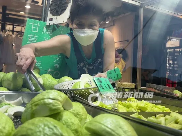 阿婆熟練地拿著夾子，夾取客人點的水果準備切。特勤中心攝