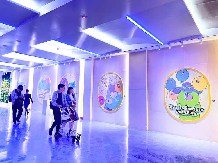 人氣插畫家KINGJUN特別為了昇恆昌免稅商店獨家設計圖素，並在松山、桃園及台中三大機場文化藝廊設展；圖為旅人經過桃園機場A區展區觀展照片。業者提供