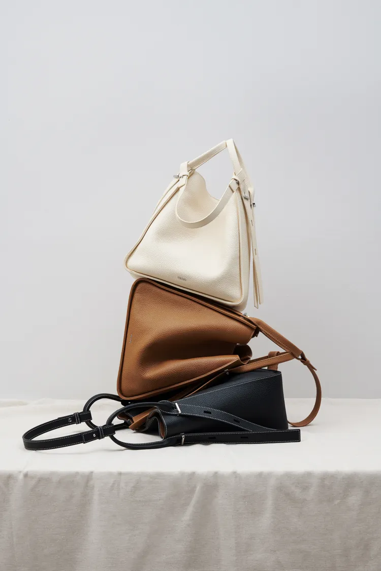 Demi皮質鬆垮包融合俐落梯形輪廓與圓潤剪裁。品牌提供