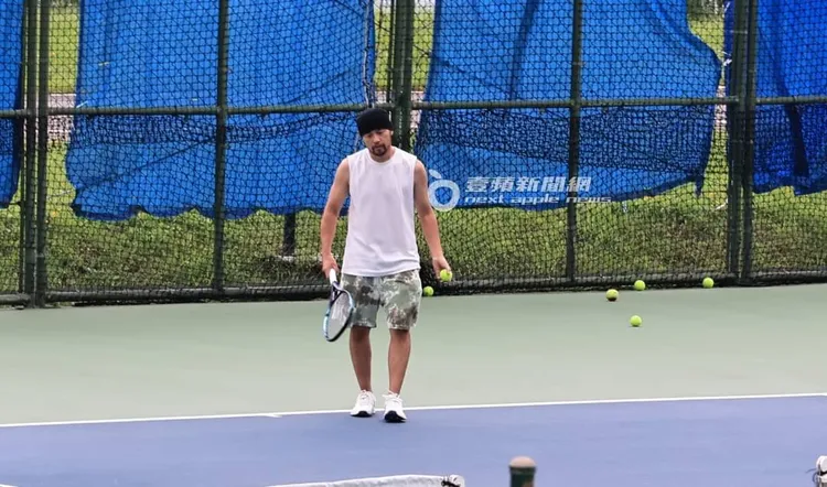 周杰倫身穿白色無袖上衣、迷彩短褲，搭配招牌頭巾現身網球場練球。特勤中心攝