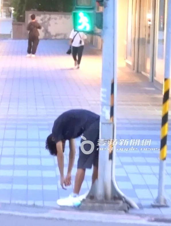 唐治平將身體靠著紅綠燈桿，彎著腰垂下雙手，聽著音樂放鬆自我。特勤中心攝