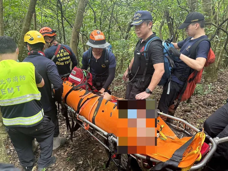 消防人員使用捲筒式擔架將男子運下山。消防局提供
