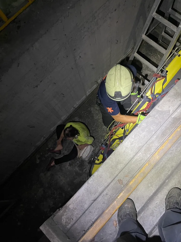 消防人員架梯救援摔落機械停車位下層的婦人。民眾提供