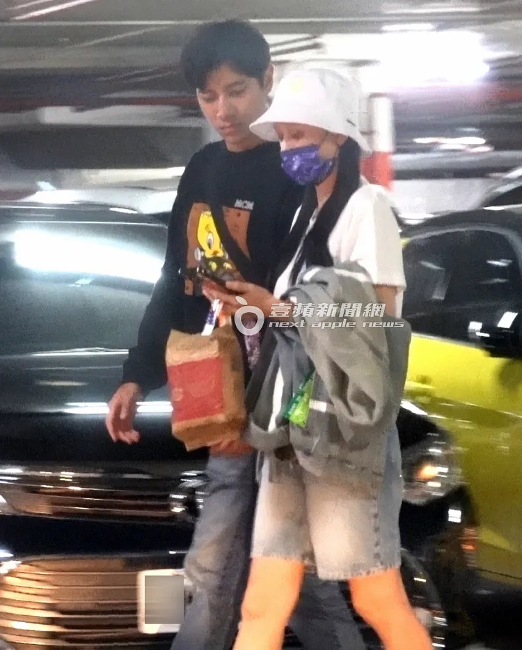 夫妻倆看著手機準備搭電梯上樓。特勤中心攝