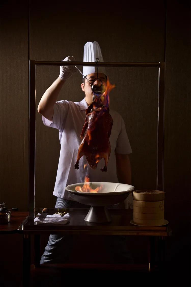 以白蘭地燒灼澆淋燒鵝、開腹噴香後，現場桌邊片鵝，十足一場食境表演秀。業者提供