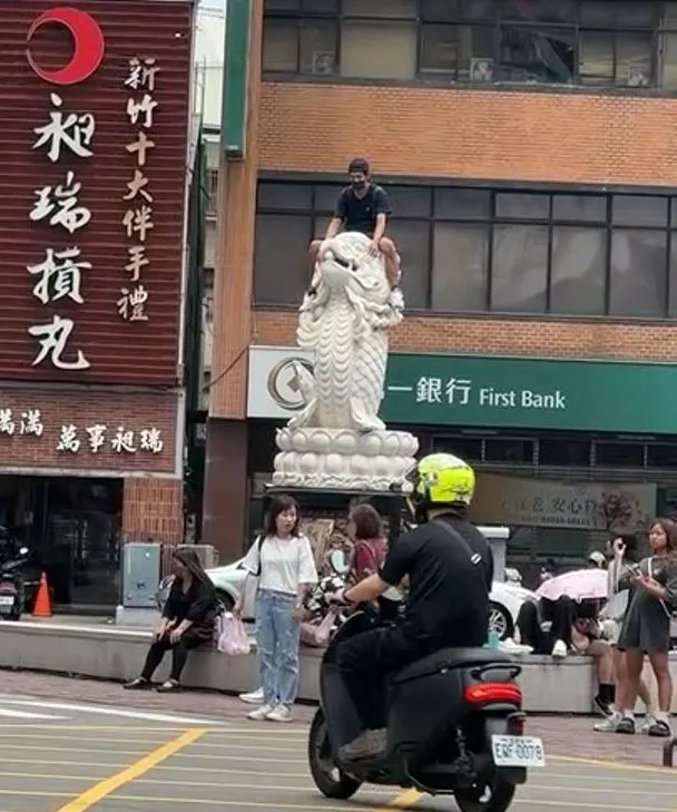 男子騎上新竹城隍廟前的龍鯉頭上。翻攝臉書《路上觀察學院》社團