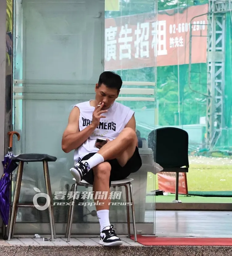 陳世念把握休息時間，到門口翹起二郎腿抽菸滑手機。特勤中心攝