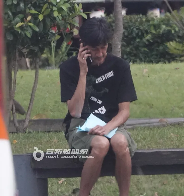 唐治平抓著母親死亡證明文件，在公園內打電話聯絡事情。特勤中心攝