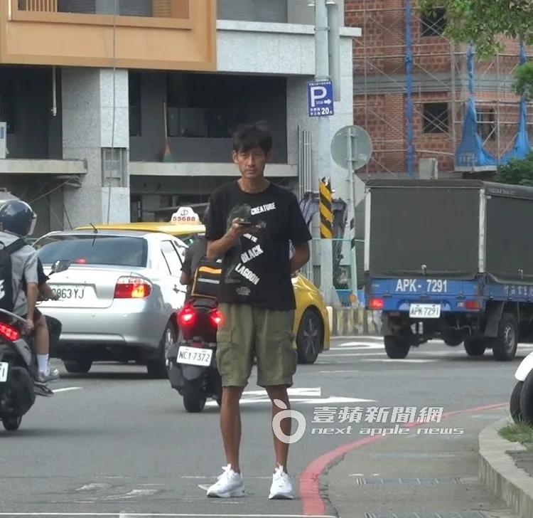 唐治平將媽媽死亡證明書放在身後，拿著手機站在馬路上等公車來。特勤中心攝