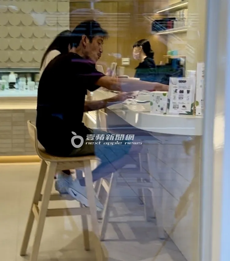 唐治平坐在店內吧台區高腳椅上，品嚐雙球精品優格冰淇淋大快朵頤。特勤中心攝