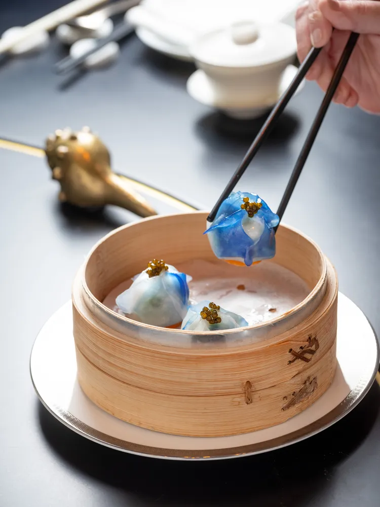 新午間單點點心「魚子醬彩蝶餃」以蝶豆花渲染上夢幻蘭紫的晶透外皮，內餡則是鮮蝦肉與爽脆的山蘇，綴以魚子醬的鮮醇。業者提供