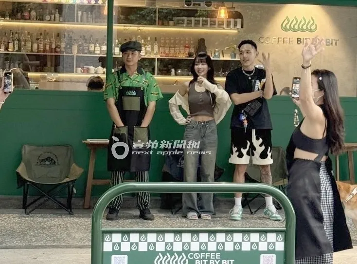 林襄（中）夾在兩名男店員中間拍照。特勤中心攝