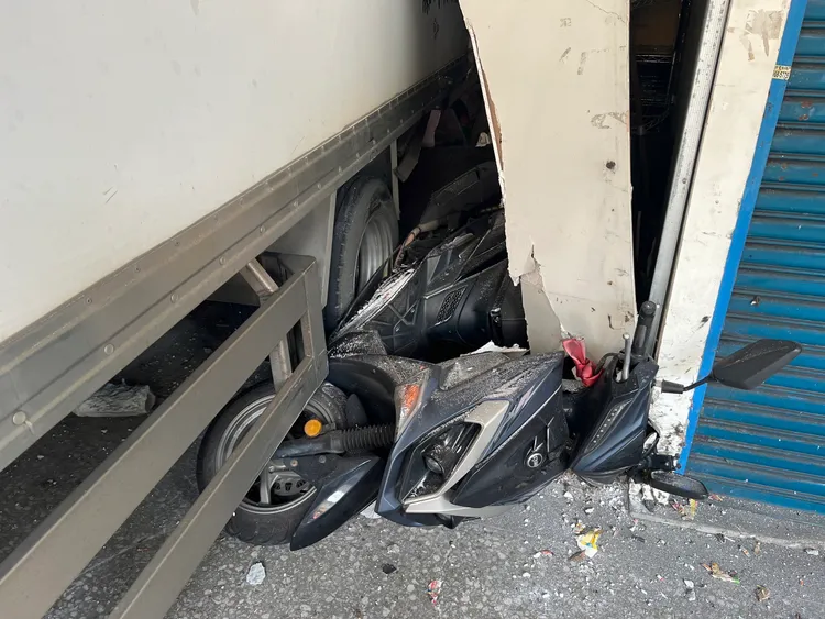 機車被捲入車底可見撞擊力之大，所幸地點是空置店面，無人受傷。翻攝畫面