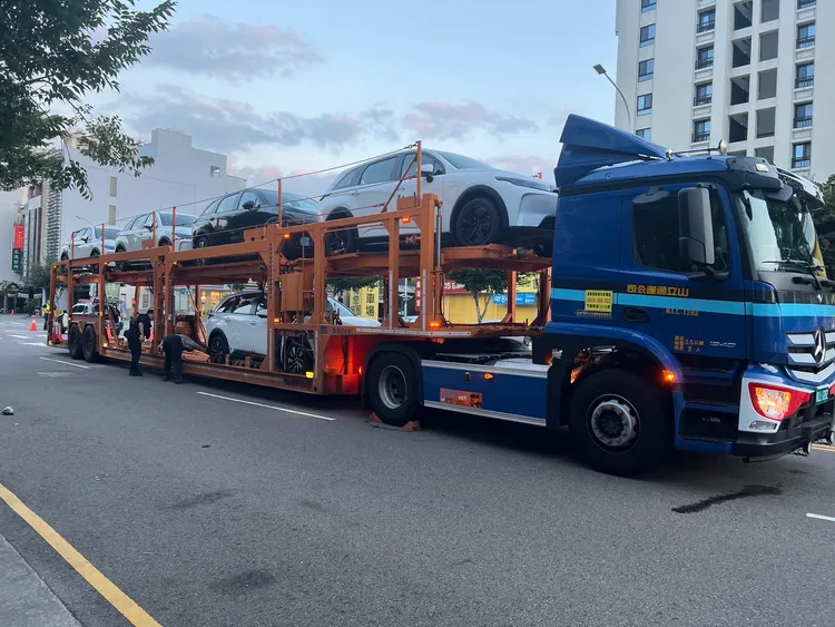 滿載新車的拖板車經過路口時速度並未放慢，與機車撞個正著。民眾提供