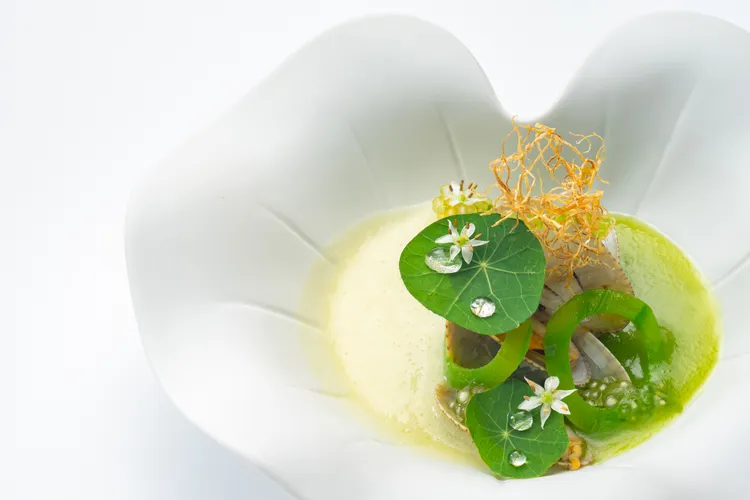 以蛤蠣為主角，搭配夏季盛產的絲瓜，模擬日本料理中的碗物。首先將絲瓜的綠皮白芯分開處理，放大絲瓜的鮮甜，加入羅勒油，最後點綴薑絲，擺盤呈現出夏日池塘意象，無論視覺或味覺，都非常具有台灣意象。業者提供。業者提供