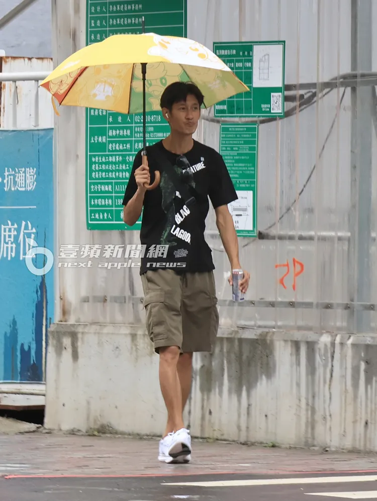 唐治平一手撐著寶可夢圖樣的傘，一手拿著能量飲料。攝影中心攝
