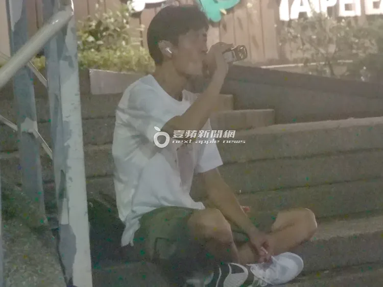 唐治平坐在階梯，敬天敬地後喝著剛買的酒。攝影中心攝