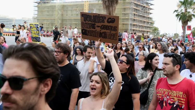 當地居民示威情況，告示牌上寫著「遊客滾蛋」。路透社