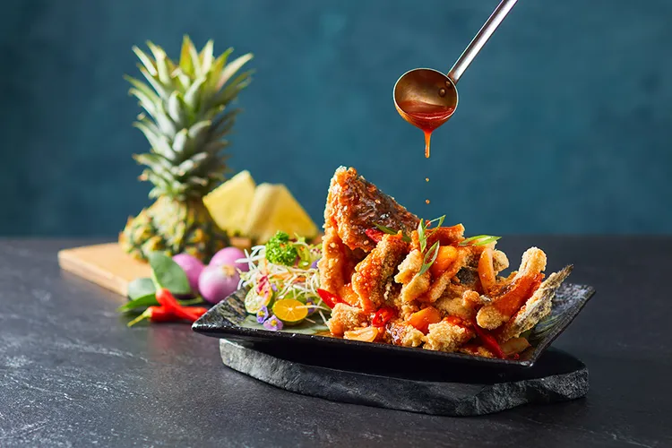 「印尼糖醋鳳梨鮮鱸魚」主廚特選海鱸魚，裹上麵衣、炸至金黃酥脆，再與鳳梨、紅椒青椒，及酸甜滋味的特製糖醋醬料拌炒，飽滿的魚香、醬香，經典必吃。業者提供