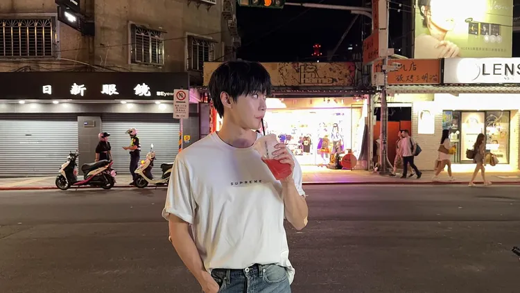 道英在士林路邊喝西瓜汁拍照留念，背後警方取締女騎士意外入鏡。翻攝道英IG