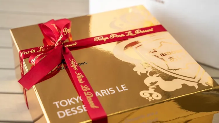 東京巴黎甜點「金莎菠蘿蛋黃酥」9入亮金色禮盒外盒更搭配精美紅色燙金印花緞帶，並會打上蝴蝶結裝飾縈繞盒面(5入可以加價購緞帶)。業者提供